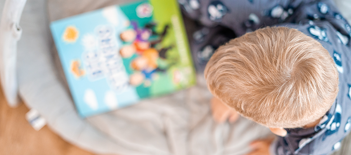 Preschool boy siting down with book in front of him