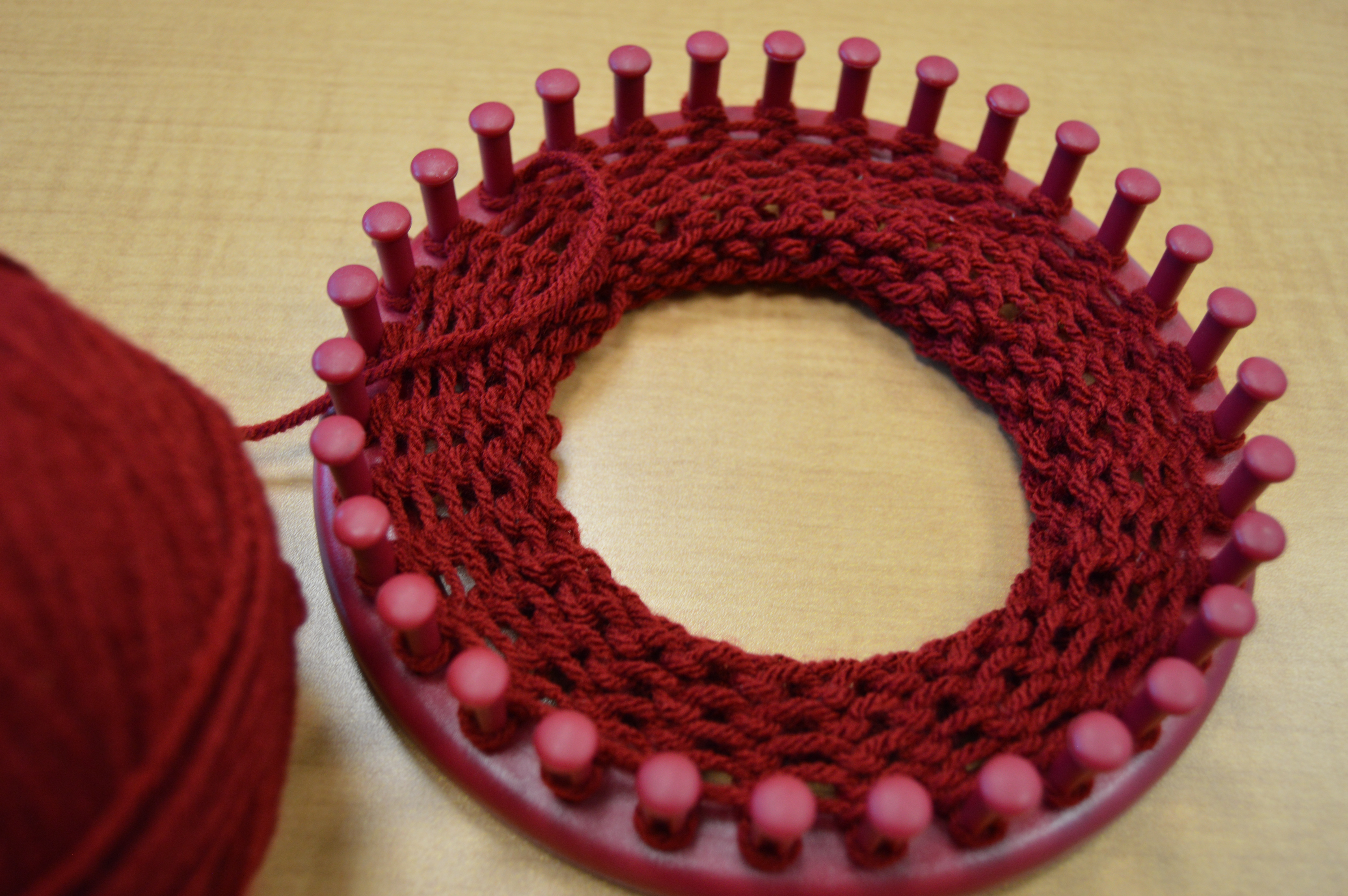 Round knitting loom with red yarn