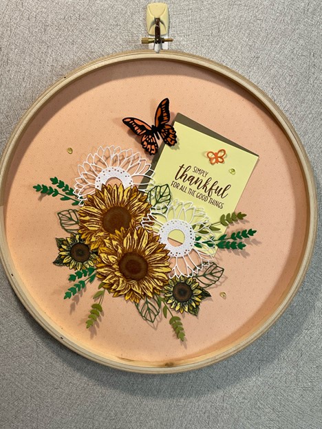 an embroidery hoop with sunflowers and butterflies on cardstock inside it.